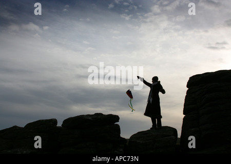 Silhouette d'girl flying kite on Hay Tor roches, Dartmoor, Devon, England UK Banque D'Images