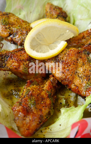 Ailes de poulet au poivre et au citron sur le dessus de la laitue dans un panier Banque D'Images