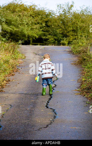 Petit Enfant à marcher le long de la route de crack Banque D'Images