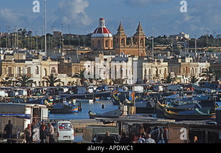 Bateaux de pêche maltais traditionnel appelé Luzzus amarré dans le port de Marsaxlokk église Notre-Dame de Pompéi dans l'arrière-plan Malte Banque D'Images