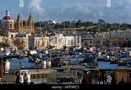 Bateaux de pêche maltais traditionnel appelé Luzzus amarré dans le port de Marsaxlokk église Notre-Dame de Pompéi dans l'arrière-plan Malte Banque D'Images