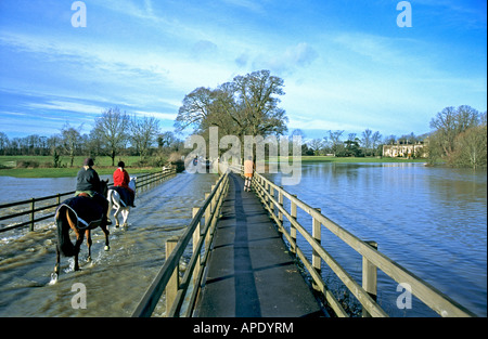 Les cavaliers à travers l'eau d'inondation à Lacock, Wiltshire UK Banque D'Images