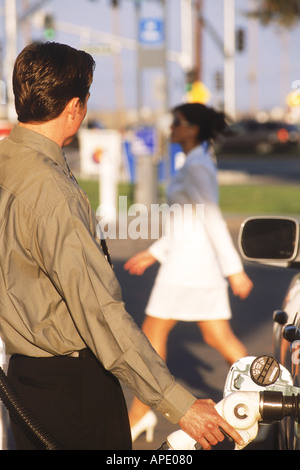 Homme à la pompe à gaz en Californie station d'essence libre-service passant regardant femme Banque D'Images