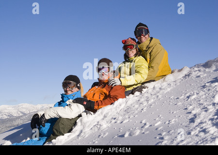 Quatre smiling friends sitting dans la neige sur une journée ensoleillée à Northstar ski resort en Californie. Banque D'Images
