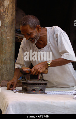 Planche Homme' Indian man ironing clothes pour une vie avec le charbon, fer à repasser dans le marché. La ville de Bharatpur. Le Rajasthan. L'INDE Banque D'Images