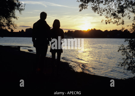 Un couple d'admirer le coucher du soleil sur le lac de Chiemsee en Bavière. Banque D'Images