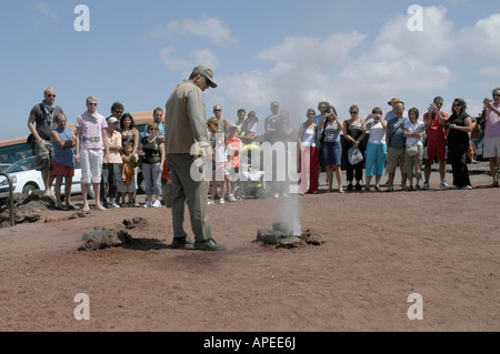 Les touristes profiter d'une démonstration de la température volcanique au Parc National de Timanfaya en Lazarote Banque D'Images