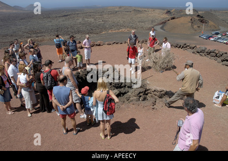 Les touristes profiter d'une démonstration de la température de la terre susceptible d'enflammer la paille au Parc National de Timanfaya en Lazarote Banque D'Images