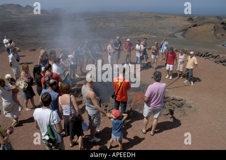 Les touristes profiter d'une démonstration de la température de la terre susceptible d'enflammer la paille au Parc National de Timanfaya en Lazarote Banque D'Images