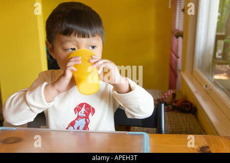 Asian boy drinking from cup Banque D'Images