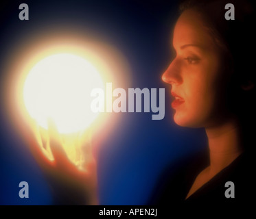 Femme regarde en boule de lumière rougeoyante. Banque D'Images