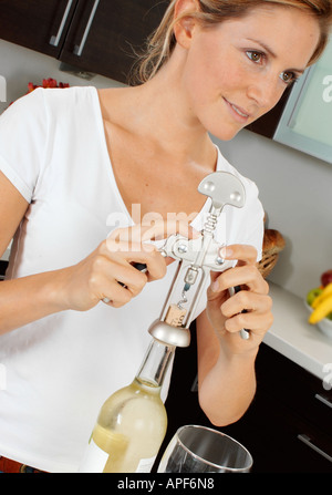 Femme EN CUISINE OUVRANT UNE BOUTEILLE DE VIN Banque D'Images