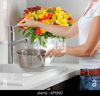 Remplir la casserole avec de l'eau FEMME Banque D'Images