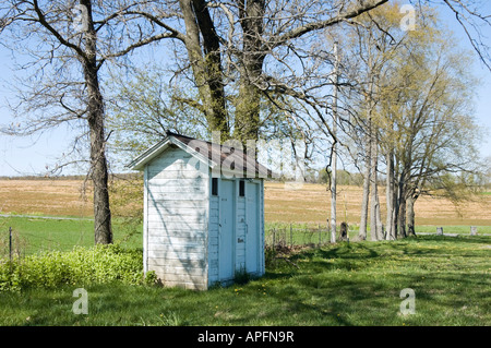 Pays outhouse sous les arbres au printemps sur une journée ensoleillée à côté de champs de ferme dans la campagne de Pennsylvanie, PA, USA. Banque D'Images