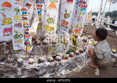 Jeune garçon encens d'éclairage sur un sable stupa construit sur la rive du Mékong à célébré le Nouvel An Luang Prabang au Laos Banque D'Images