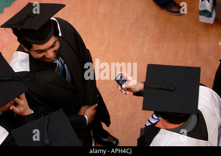 Diplômes : les diplômés dans des robes de l'envoi de messages sur leur téléphone mobile. Photo par Jim Holden. Banque D'Images