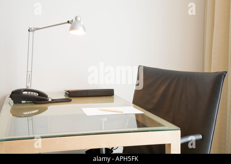 Bureau avec lampe et chaise pivotante en cuir noir. Pourrait représenter un bureau 24, l'étude à la maison ou chambre d'hôtel. Banque D'Images