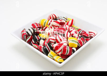 Un bol de bonbons durs tourné sur blanc très coloré et des couleurs saturées. Banque D'Images