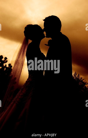 Mariée et le marié hug après le mariage en silhouette au coucher du soleil Banque D'Images