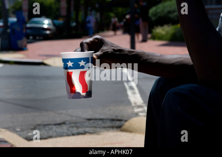 Bras de mendiant, panhandler, holding out paper cup avec nous sur la décoration du pavillon de la rue de Washington DC. Lumière arrière avec ombre de l'argent. Banque D'Images