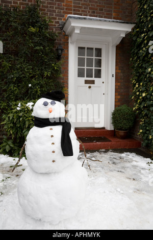 Le Snowman à la porte d'une maison en hiver Banque D'Images