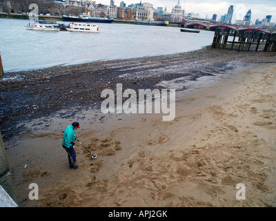 Un homme à l'aide d'un détecteur de métal sur la rive sud de la rivière Thames. London England UK Banque D'Images