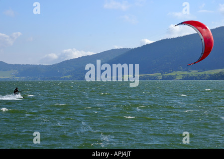 Les vitesses d'un kite surfer à travers un lac de montagne en Suisse. L'espace pour le texte sur le ciel en haut à gauche. Banque D'Images