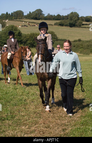 Petite fille âgée de huit ÉQUITATION ÉQUITATION PONEY DANS OUTFIT VÊTEMENTS AVEC DES ADULTES À PONY PONY CLUB MANIFESTATION UK Banque D'Images