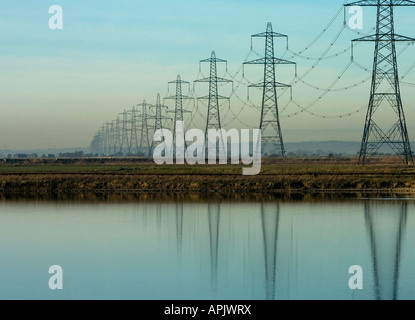 Pylônes électriques se reflètent dans l'eau sur Romney Marsh dans le Kent dans le sud de l'Angleterre l'énergie est fournie par l'énergie nucléaire à la station Banque D'Images