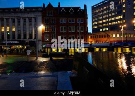 Une partie de la fontaine d'eau à la place du marché se trouve une piscine de l'eau, qui comme on peut le voir sur cette image donne de bonnes réflexions surtout la nuit. Derrière le dispositif de l'eau l'un des trams Nottinghams peut être vu en passant. Place du marché, Nottingham, Royaume-Uni Banque D'Images