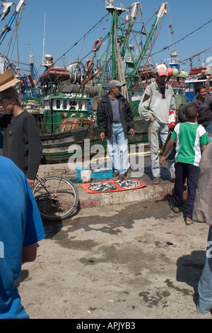 Vente pêcheur de sardines sur le quai avec des bateaux de pêche dans l'arrière-plan Banque D'Images