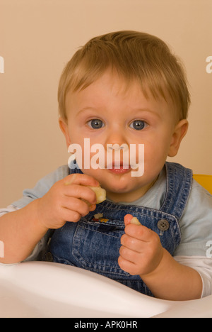 Bébé garçon 10 mois Eating fruit Banque D'Images