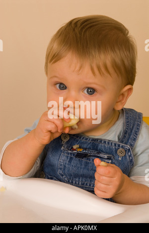 Bébé garçon 10 mois Eating fruit Banque D'Images