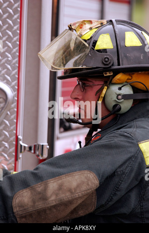 MPO Un pompier avec un casque à la commande d'un camion de pompiers le pompage de l'eau à la scène Banque D'Images