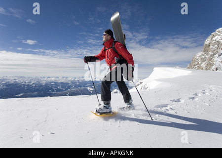 Man with snowboard sur le dos à la raquette dans les montagnes, Autriche Banque D'Images