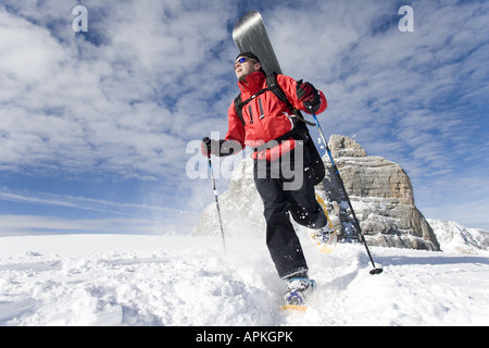 Man with snowboard sur le dos à la raquette dans les montagnes, Autriche Banque D'Images