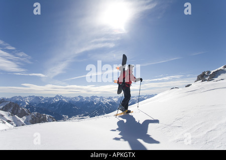 Man with snowboard sur le dos à la raquette dans les montagnes, Autriche Banque D'Images