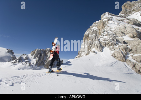 Man with snowboard sur le dos à la raquette dans les montagnes, Autriche Banque D'Images