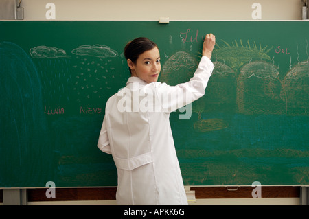 Dans une salle de classe de l'enseignant écrit sur tableau noir Banque D'Images