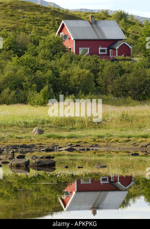 Maison typiquement scandinave de couleur rouge à un petit lac sur le Vetsvagoy reflétant dans un fjord, Norvège, îles Lofoten, Vetsvagoy Banque D'Images