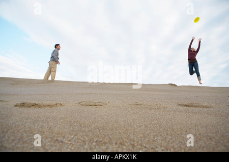 L'homme et la femme jetant sur frisbee beach (low angle view) Banque D'Images