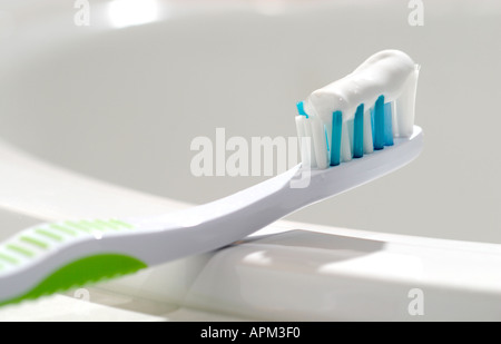 Brosse à dents avec du dentifrice en appui sur le bord de l'évier Banque D'Images