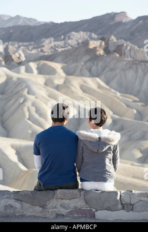 Couple assis sur le mur de pierre en désert (vue arrière) Banque D'Images