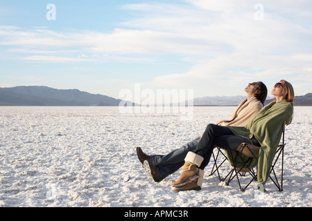 Couple assis sur des chaises longues dans le désert Banque D'Images
