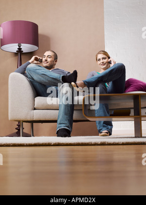 Jeune couple sur les téléphones portables sur canapé Banque D'Images