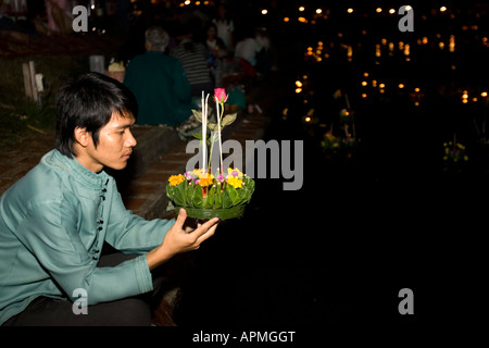 Jeune homme se prépare à flotter un Krathong radeau illuminé Jong Kham Lac de Mae Hong Son, Thaïlande Banque D'Images