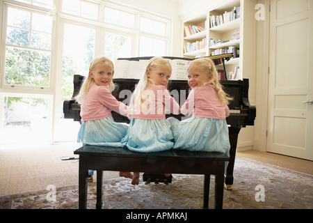 Des triplés à jouer du piano dans la salle de séjour (vue arrière) Banque D'Images