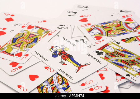 Nouveau jeu de cartes à jouer dispersées sur un fond blanc avec l'accent sur la carte joker sur le haut de la pile pile Banque D'Images