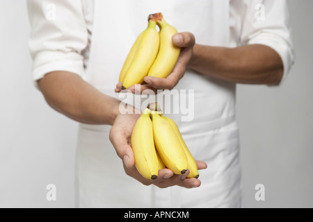 Chef holding régimes de bananes (mid section) Banque D'Images