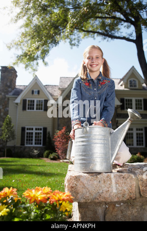 Girl (10-11) avec l'arrosoir debout par flower bed, Chatham, New Jersey, USA Banque D'Images